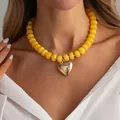 Primer plano de collar de cuentas de resina amarilla con colgante de corazón dorado - Oro + Amarillo