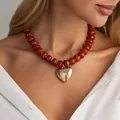 Κομψό κολιέ με πορτοκαλί χάντρες ρητίνης και χρυσό μενταγιόν καρδιά φορεμένο σε μοντέλο - Χρυσό + Καφέ
