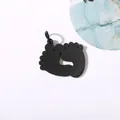 Macro view of a black mirror-polished stainless steel baby footprint charm DIY pendant - Black