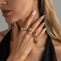 Gedetailleerde macro-opname van kleurrijke kristallen gouden ringen aan de hand van een model. - Lichtgoud Stijl (Set van 8)