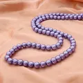 Perles d'imitation rondes violettes sur tissu de soie pour la création de bijoux. - Violet
