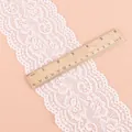 Detailansicht der breiten weißen elastischen Spitzenborte mit Blumenmuster und Lineal - Elastische Spitzenborte Breite 10cm / 2 Yards / Weiß