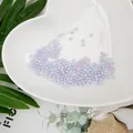 Vista detallada de perlas de imitación ABS iridiscentes en un plato con forma de corazón - Diámetro 4mm (Aprox. 500pcs) / Multicolor Rosa Púrpura Azul Cielo