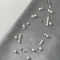 Macro detail of double-layered starry sky pearl necklace on textured grey silk background - Double Layer Starry Pearl Style / Cream White Pearl / Transparent Line