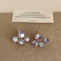 Vista detallada de pendientes de flor de cristal iridiscente con baño de oro elegante - Pendientes Púrpuras Idiscentes