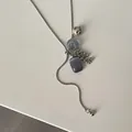Close-up of spotted stone and grape cluster charms on a silver snake chain necklace - Purple