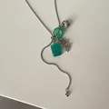 Macro view of silver snake chain lariat necklace with dalmatian stone and green resin charms - Green