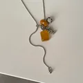Detail of long snake chain necklace with Dalmatian stone and amber-toned charms - Yellow