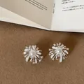 Detailed close-up of silver-toned firework stud earrings with center pearl and zircon - Style 9 Earrings