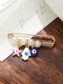 Detailed macro shot of a gold-tone safety pin brooch with pearls and evil eye charms - Pink White Blue Classic Pin Style (my6)