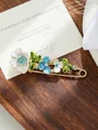 Dettaglio di un'elegante spilla a fiore con petali in smalto e strass scintillanti. - Modello tulipano bianco e azzurro (A17-13)