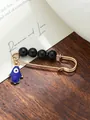 Detailed view of a gold Hamsa Hand brooch with black beads and blue evil eye charm - Hamsa Hand Single Charm Style (my9)