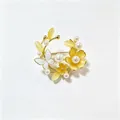 Gedetailleerde macro-opname van een vintage bloemenbroche met parels en gele stenen - Geel