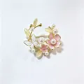 Elegante cirkelvormige bloemenkrans broche met parels en roze emaille bloemen voor pakken. - Roze