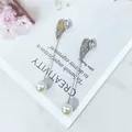 Detailansicht von Strass-Flügel-Anstecknadeln mit weißen Perlen auf Marmoruntergrund - Flügel Welle (Y1-07)