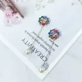 Nahaufnahme von bunten Strassblumen- und Perlen-Anstecknadeln auf Magazin-Hintergrund - Bunte Strass Blume (Y1-13)