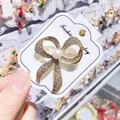 Detailansicht einer goldenen Schleifenbrosche mit Strasssteinen und einer Perle - Eleganter Schleifen-Stil