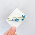 Elegante goldene Schmetterlingsbrosche mit blauen Kristallen auf einer Schmuckkarte - Schmetterlings-Stil (DZ02511) / Blau
