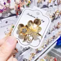 Detailed close-up of a golden flower brooch with a central pearl and rhinestone accents - Flower Style