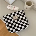 Primer plano de una bolsa de lona a cuadros blancos y negros en un entorno minimalista - Bolsa de maquillaje / Tablero de Ajedrez Blanco y Negro