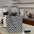 Bolso de lona con diseño de cuadros blancos y negros mostrado en una acogedora cafetería. - Bolso Tote (Estilo Coreano) / Tablero de Ajedrez Blanco y Negro