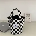 Primer plano de un bolso de lona con diseño de tablero de ajedrez en blanco y negro en un escritorio - Bolso de Cubo Pequeño / Tablero de Ajedrez Blanco y Negro