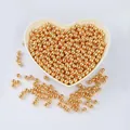 Close-up of 14K gold-filled smooth round beads in a heart-shaped dish for DIY jewelry - 2.5mm 100 Pieces/Pack / 18K Gold Plated