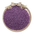 Kleine lila glänzende Glasperlen für DIY-Schmuck in einem goldenen Tablett gezeigt - Dunkelviolett