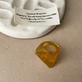 Detail view of an amber resin ring featuring a bold geometric faceted cut design. - Faceted Smudge Ring / Light Coffee