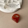 Detailed view of an orange marbled resin faceted ring on a minimalist background - Faceted Smudge Ring / Orange Red