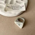 Macro shot of a geometric resin ring with a grey marble swirl and faceted texture - Faceted Smudge Ring / Off White