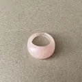 Close-up van een minimalistische lichtroze harsring met een subtiele marmeren textuur. - Roze