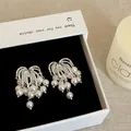 Detailed macro view of elegant silver firework-shaped earrings with cascading white pearls. - Style 32 Earrings