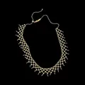 Detailed macro view of a golden mesh lace necklace with delicate bead design. - Gold