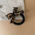 Close-up view of a vintage leopard print sponge bow on a black elastic hair scrunchie - Crisscross Bow Hair Tie (3#) / Leopard Print