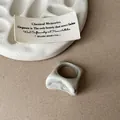 Gros plan d'une bague en résine marbrée irrégulière avec de jolis reflets gris et blancs - Bague Blanc Cassé