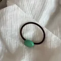 Dettaglio di un elastico per capelli nero con ciondolo ovale verde a pois rosa - Verde