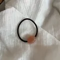 Dettaglio di un elastico per capelli marrone con una perla ovale a pois rosa - Arancione