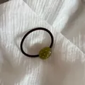 Vista detallada de una cuenta ovalada verde oliva con lunares rosas en una coleta - Verde