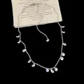 Macro detail of elegant silver necklace with dangling clear zircon tassels on black backdrop - Zircon Tassel Necklace / Gold Plated
