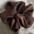 Detailed view of elegant brown polka dot scrunchie hair accessory on a beige linen background - Coffee with Dots