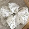 Close-up of white polka dot scrunchie with soft fabric texture and pleats - White with Black Polka Dots