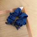 Close-up of a vintage blue scrunchie with a brown checkered bow on a wooden tray - Blue Scrunchie