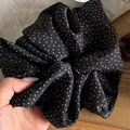 Detailed macro view of a soft black satin scrunchie featuring a white star polka dot pattern - Black with White Polka Dots