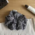 Detailed view of a stylish grey leopard print hair scrunchie on a wooden surface. - Gray with Black Polka Dots