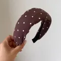 Vista dettagliata di un cerchietto marrone retrò a pois tenuto in mano. - Pois Caffè