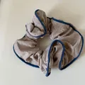 Close-up detail of beige polka dot fabric scrunchie with navy blue ruffled piping edge - Scrunchie / Gray Polka Dot Scrunchie