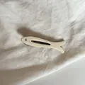 Detalle de cerca de una pinza para el pelo de pececito crema con un ojo de strass - Blanco Sólido