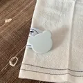 Nahaufnahme einer niedlichen hellblauen Haarklammer in Bärenform auf weißem Stoff. - 2.5cm / Grüner Bär Clip