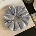 Close-up detail of a silver-blue satin scrunchie showing the glossy silk fabric texture - L / Blue